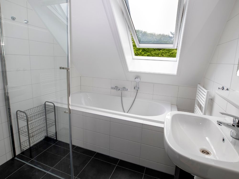 Badkamer met ligbad en dakraam op het bos